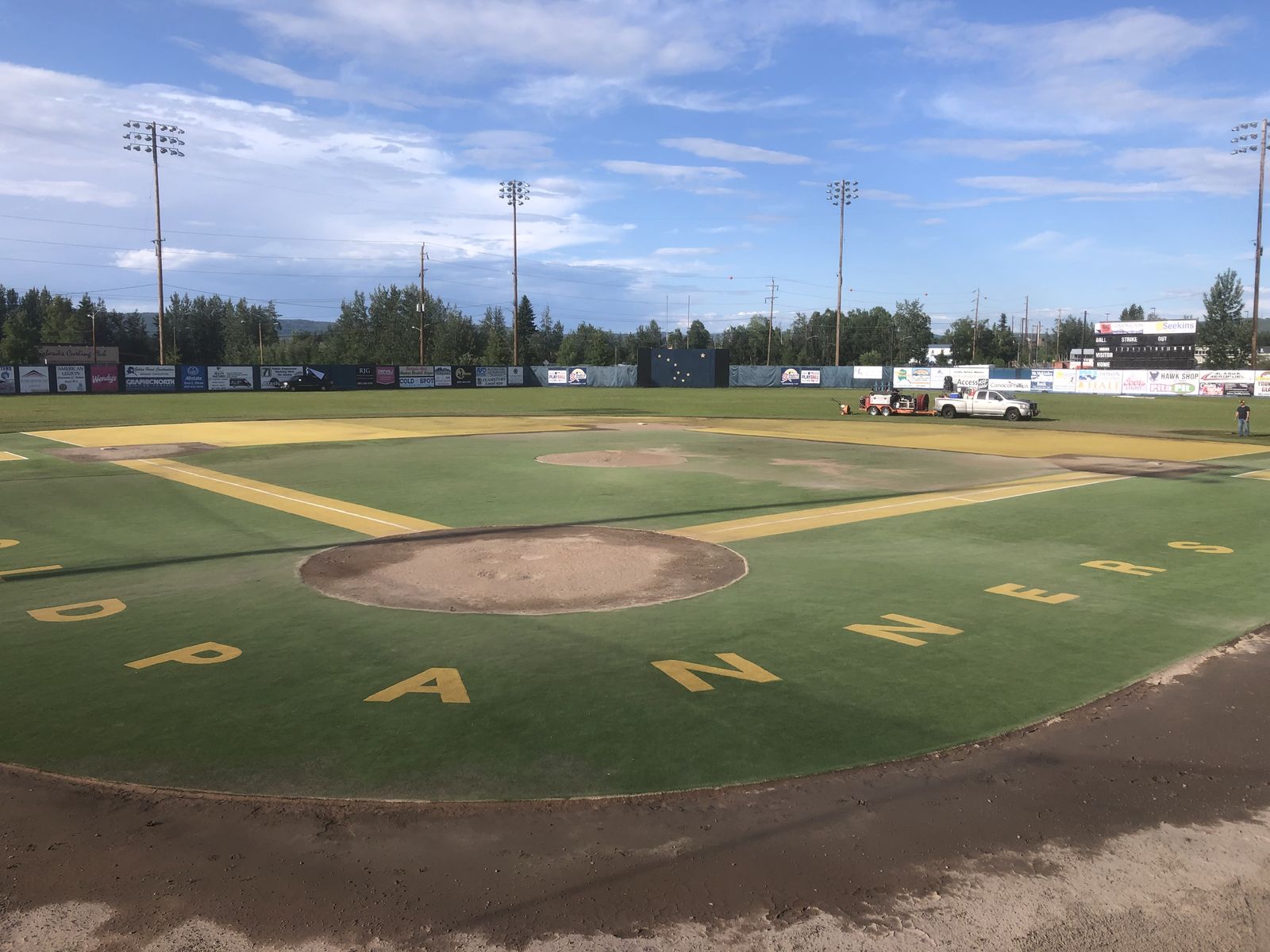 The same field's turf washed back to green, the yellow lettering around the infield bright again