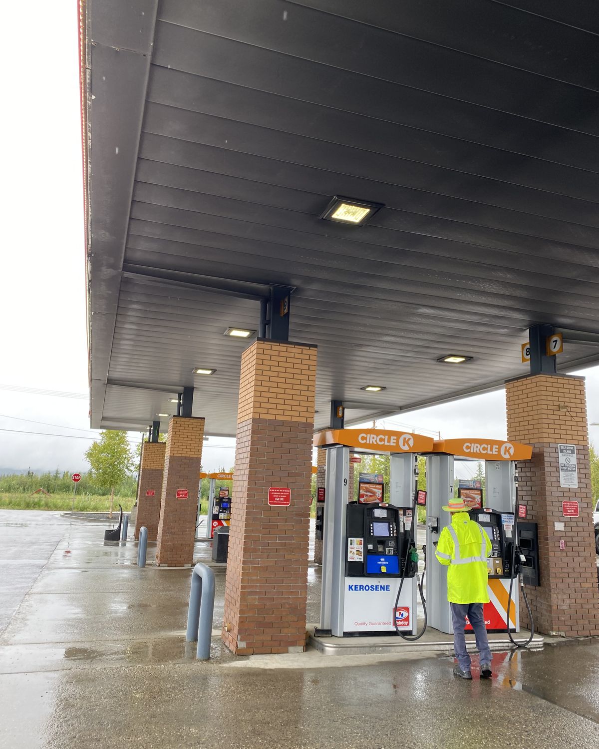 A fuel station canopy ceiling stained dark grey with soot over the pumps
