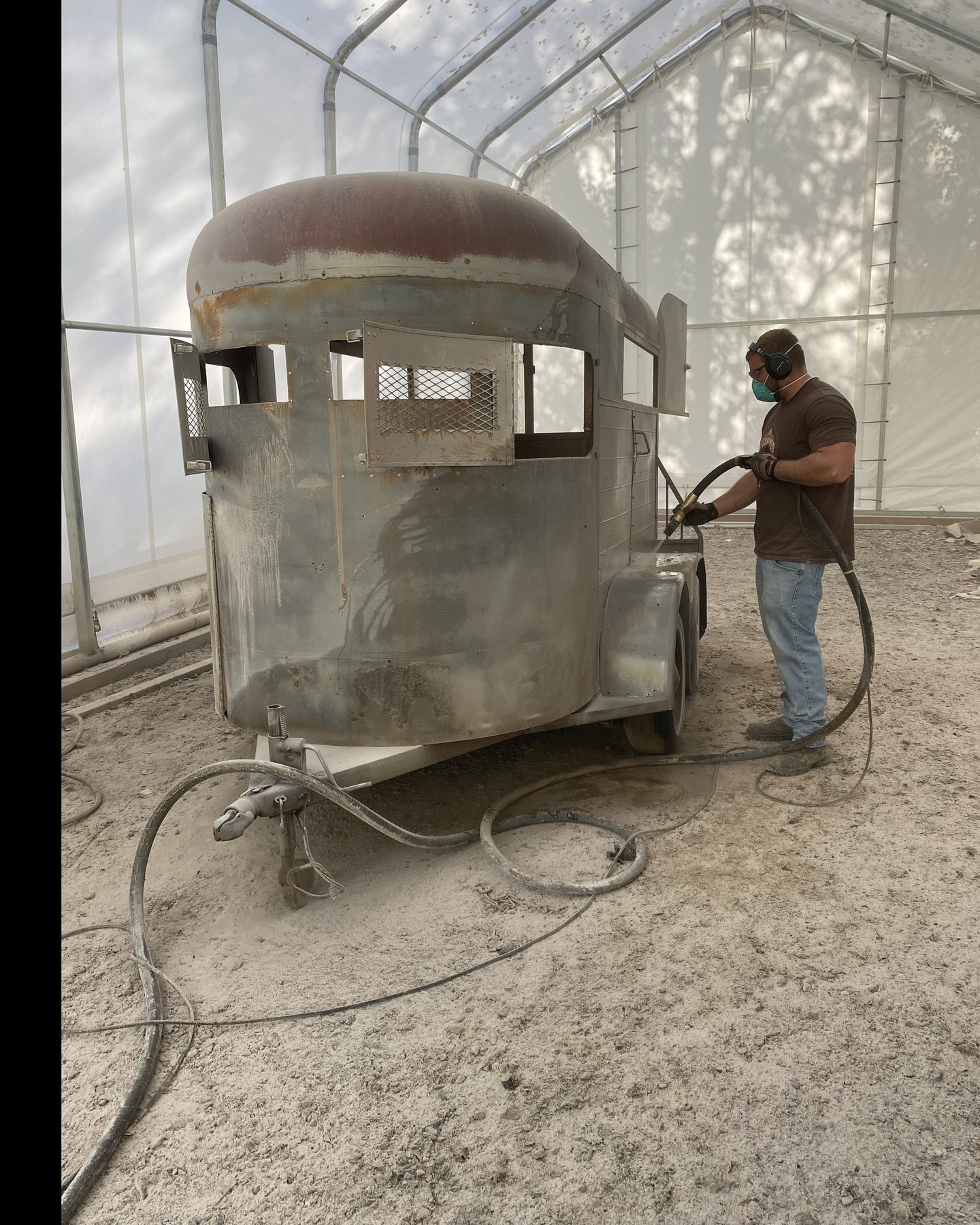 Joel's son Michael blasting a two-horse trailer back to bare panel inside a work shelter