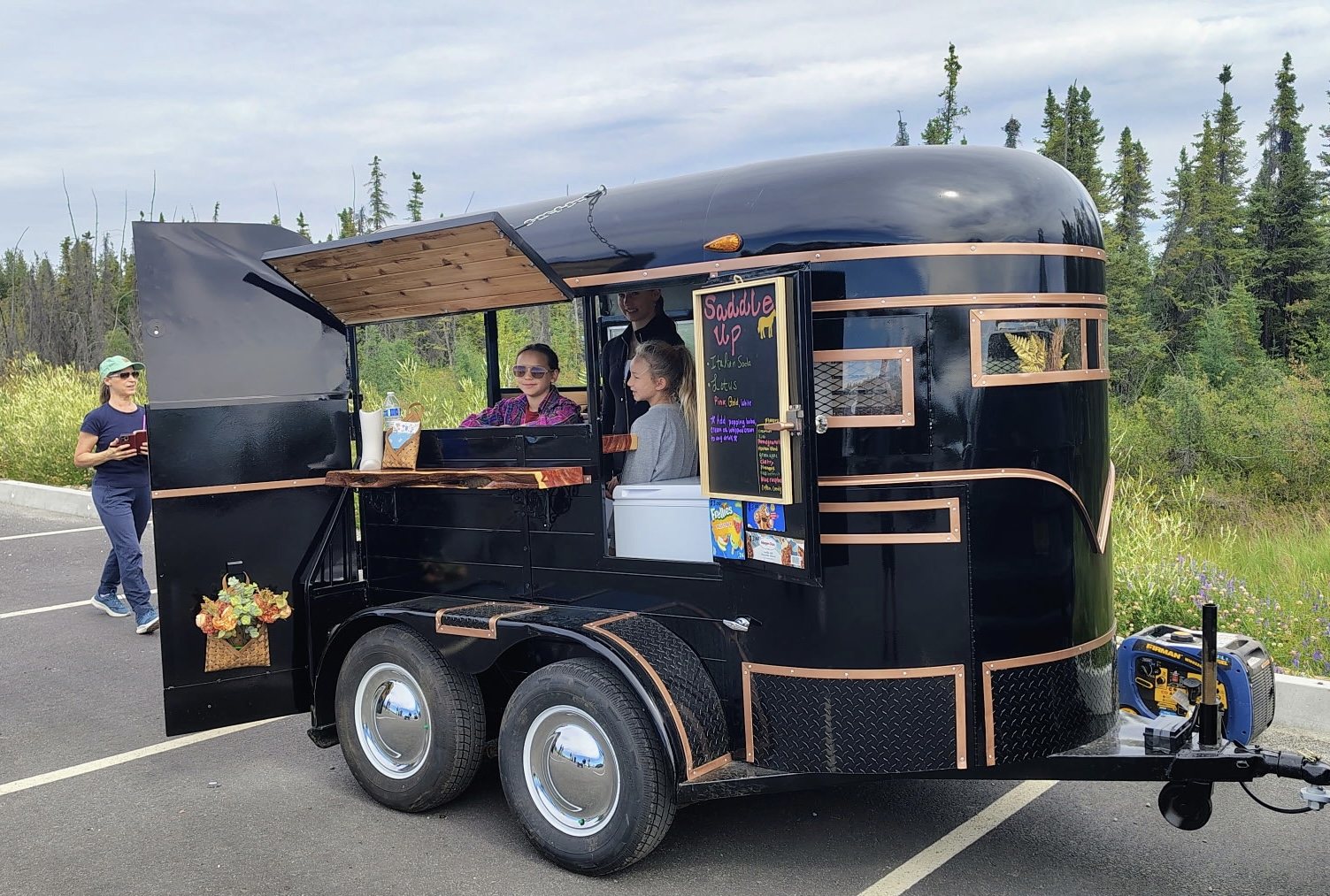 The same trailer finished in gloss black with copper trim, opened up as a drinks stand called Saddle Up, with the owner's family in and beside it